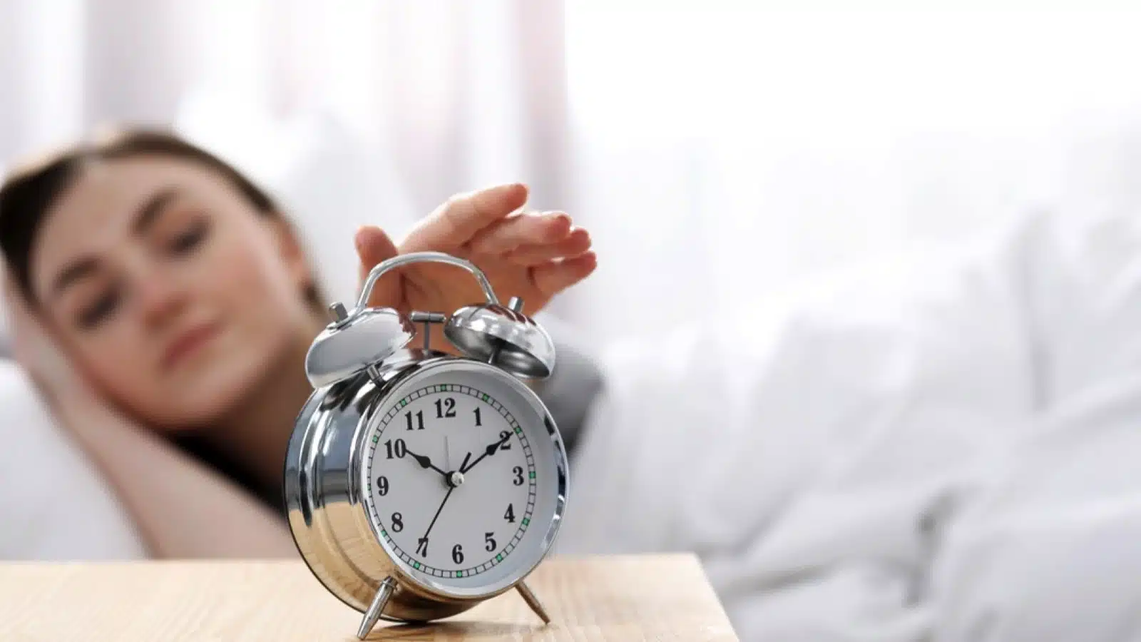 Woman switching off alarm clock