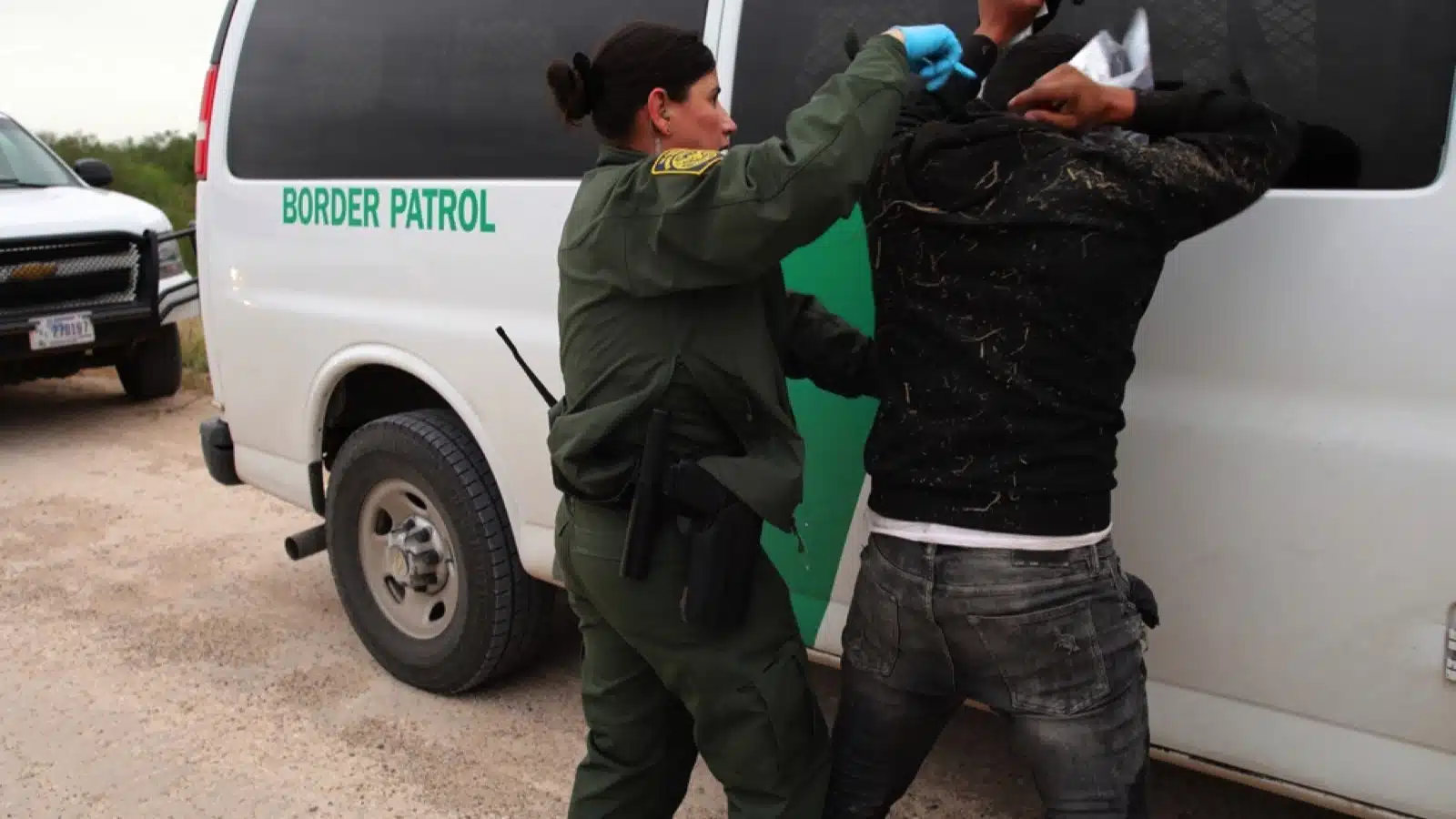 Mission, TX, USA - Feb. 16, 2023: A young Hispanic female Border Patrol agent searches a young Mexican man who crossed the Rio Grande River illegally to enter the U.S.