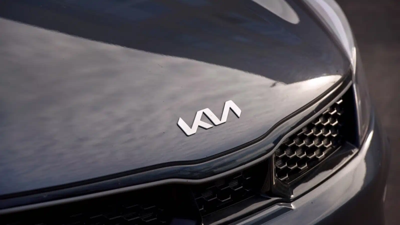Minsk, Belarus. Apr 2022. KIA Motors new angular logo on hood of dark grey Kia Rio. Chrome KIA logo close up on dark grey hood, front grille detail
