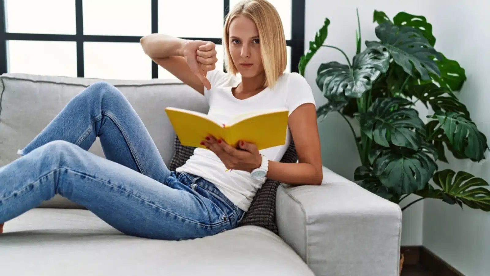 Woman reading book showing thumbs down reaction