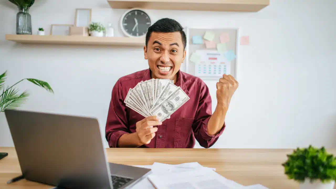 excited man with cash in home office.jpg
